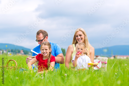 Photo: Glückliche Familie sitzt auf Wiese im Sommer Glückliche Familie sitzt auf Wiese im Sommer