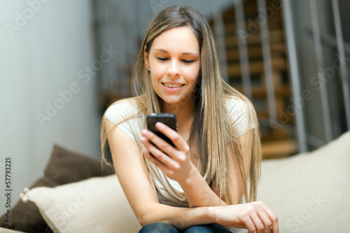 Photo: Woman reading a sms on the sofa Woman reading a sms on the sofa