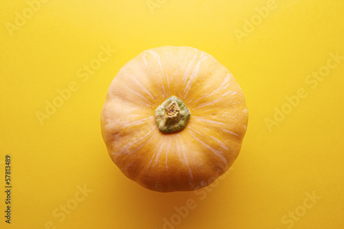 Photo: Whole raw pumpkin on yellow background Whole raw pumpkin on yellow background