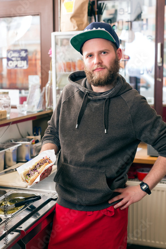Photo: salesman making hotdog in fast food snack bar salesman making hotdog in fast food snack bar