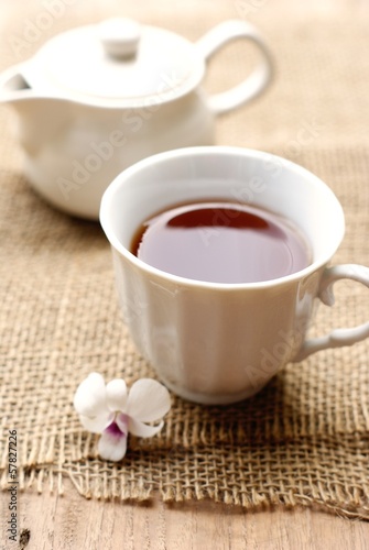 Photo: cup of tea with beautiful orchid over wooden background cup of tea with beautiful orchid over wooden background