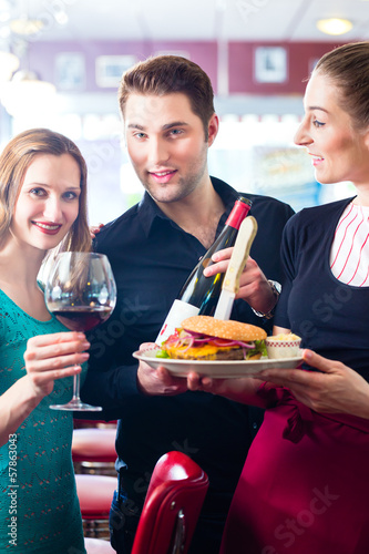 Photo: People in American diner with burger and wine People in American diner with burger and wine