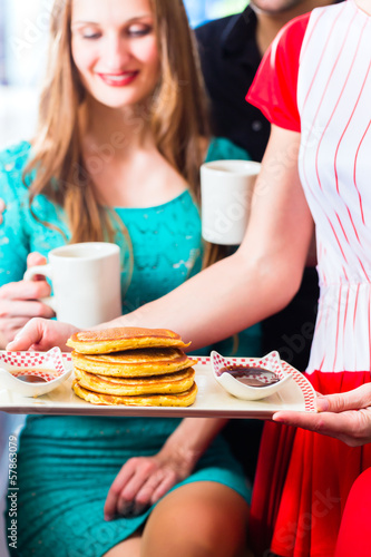 Photo: People in diner or restaurant having pancakes People in diner or restaurant having pancakes