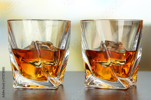 Photo: Glasses of whiskey, on bright background Glasses of whiskey, on bright background