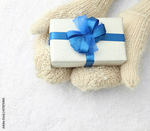 Photo: Female hands in mittens with gift box, on white background Female hands in mittens with gift box, on white background