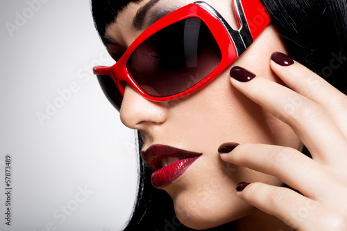 Photo: Face of a woman in red sunglasses with beautiful dark nails Face of a woman in red sunglasses with beautiful dark nails