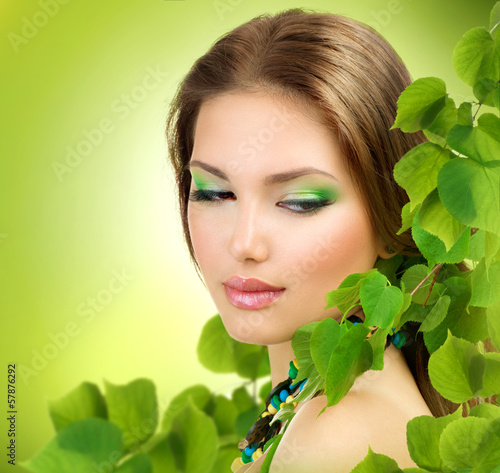 Photo: Beautiful Girl with Green Leaves. Spring Beauty outdoor Beautiful Girl with Green Leaves. Spring Beauty outdoor