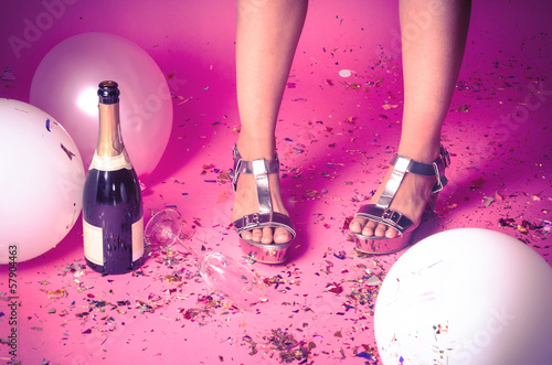 Photo: Woman's feet with confetti on the floor and champagne Woman's feet with confetti on the floor and champagne