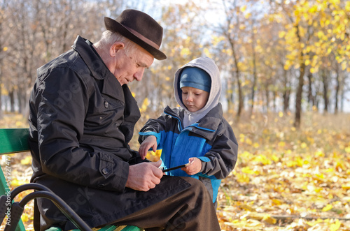 Photo: Elderly man with his grandson in the park Elderly man with his grandson in the park