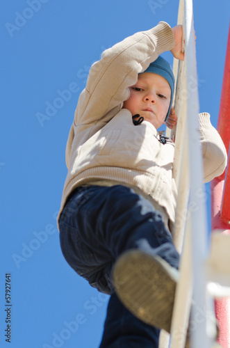 Photo: Cute active child climbing up a ladder in the park Cute active child climbing up a ladder in the park