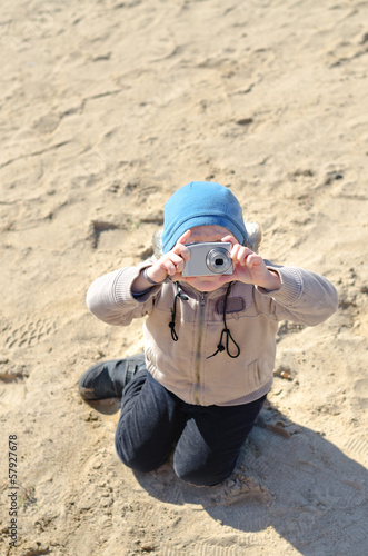 Photo: Funny little child holding a compact camera Funny little child holding a compact camera