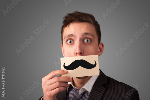 Photo: Happy businessman holding funny mustache card on his mouth Happy businessman holding funny mustache card on his mouth