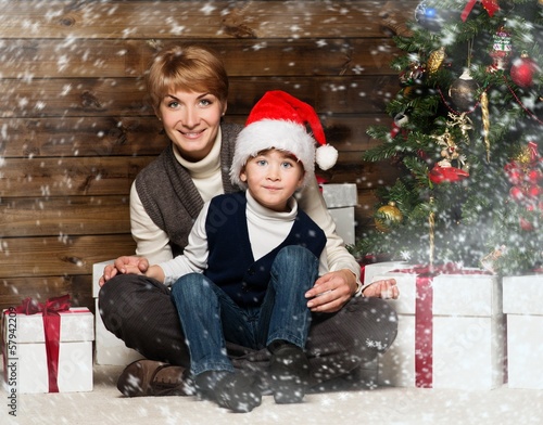 Photo: Happy mother with her child under christmas tree Happy mother with her child under christmas tree