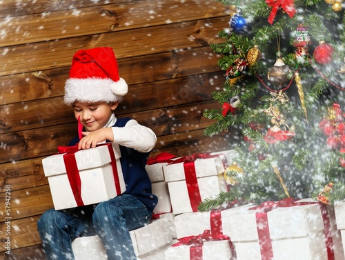 Photo: Little boy with gift box under christmas tree Little boy with gift box under christmas tree