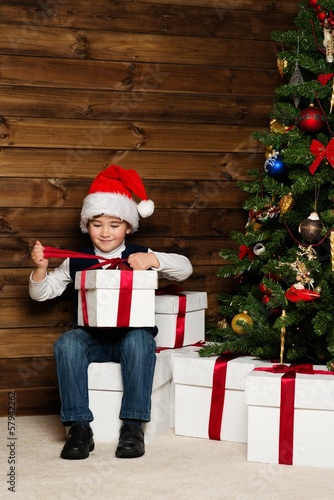 Photo: Little boy with gift box under christmas tree Little boy with gift box under christmas tree