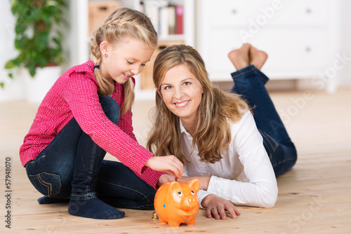 Photo: mutter und tochter füttern das sparschwein mutter und tochter füttern das sparschwein