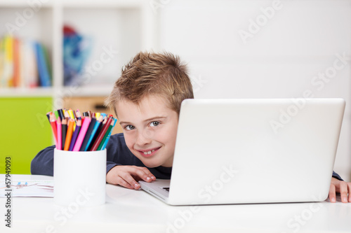 Photo: süßer junge schaut hinter laptop hervor süßer junge schaut hinter laptop hervor