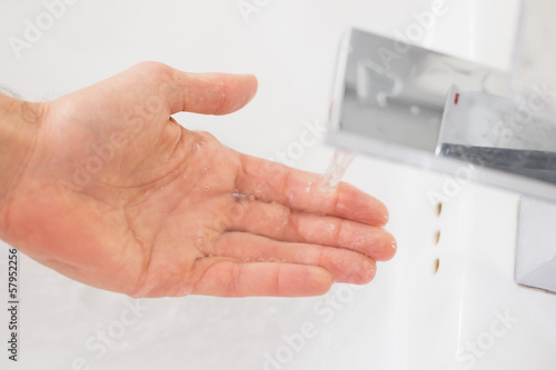 Photo: Hand under running water at bathroom sink Hand under running water at bathroom sink