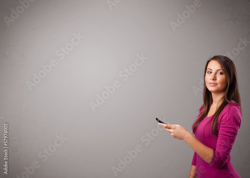 Photo: young lady standing and holding a phone with copy space young lady standing and holding a phone with copy space