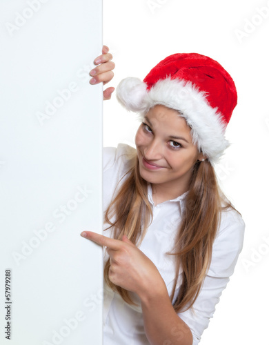 Photo: Beautiful woman with christmas hat pointing on a signboard Beautiful woman with christmas hat pointing on a signboard