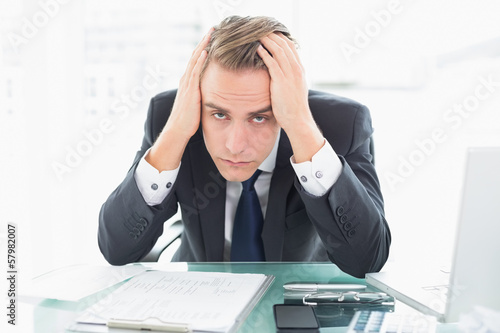 Photo: Worried businessman sitting at office desk Worried businessman sitting at office desk