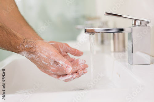 Photo: Washing hands with soap under running water at bathroom sink Washing hands with soap under running water at bathroom sink