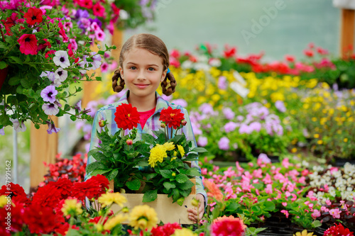 Photo: Gardening - girl holding flowers in garden center Gardening - girl holding flowers in garden center