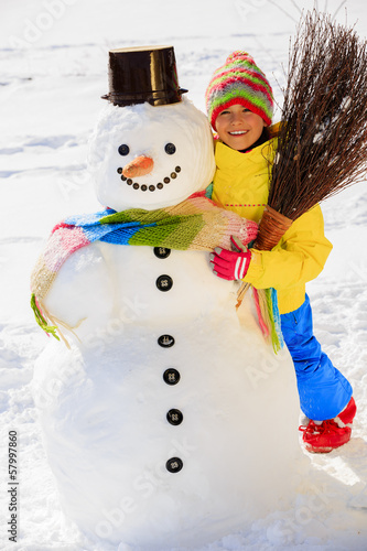 Photo: Winter fun, happy kid playing with snowman Winter fun, happy kid playing with snowman