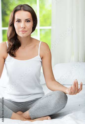 Photo: Young beautiful woman meditating, indoors Young beautiful woman meditating, indoors
