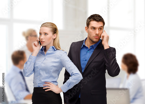 Photo: woman and man with cell phones calling woman and man with cell phones calling