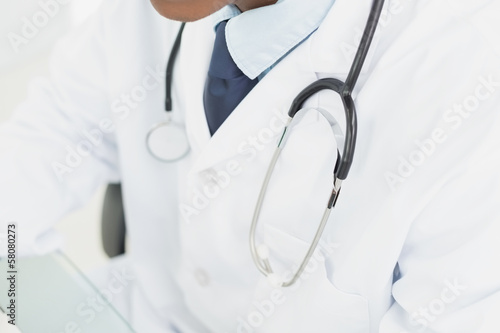 Photo: Mid section of doctor in lab coat and with stethoscope Mid section of doctor in lab coat and with stethoscope