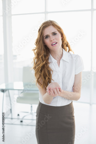 Photo: Young businesswoman suffering from wrist pain in office Young businesswoman suffering from wrist pain in office
