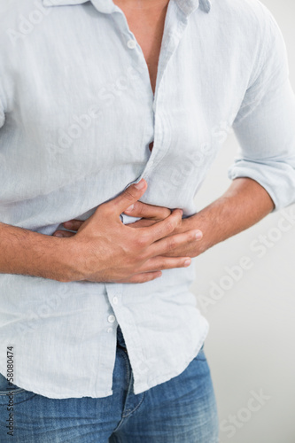 Photo: Mid section of man suffering from stomach pain Mid section of man suffering from stomach pain