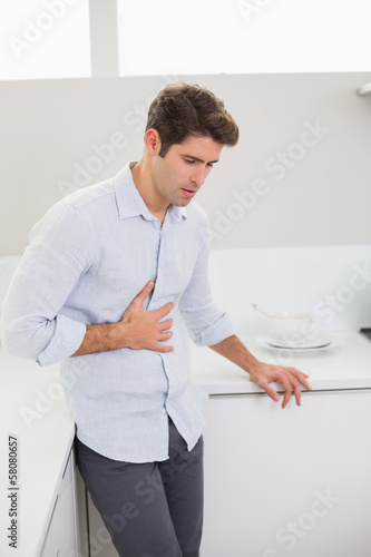 Photo: Casual man with stomach pain in the kitchen Casual man with stomach pain in the kitchen