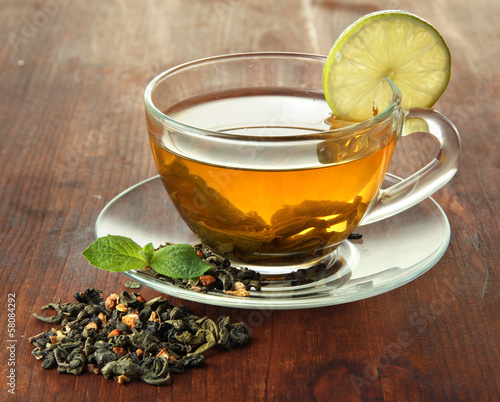 Photo: Transparent cup of green tea with lime on wooden background Transparent cup of green tea with lime on wooden background