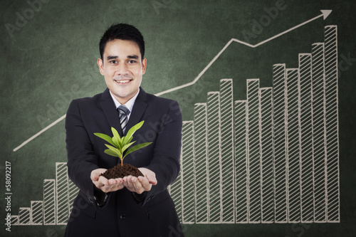 Photo: Businessman holding a plant Businessman holding a plant