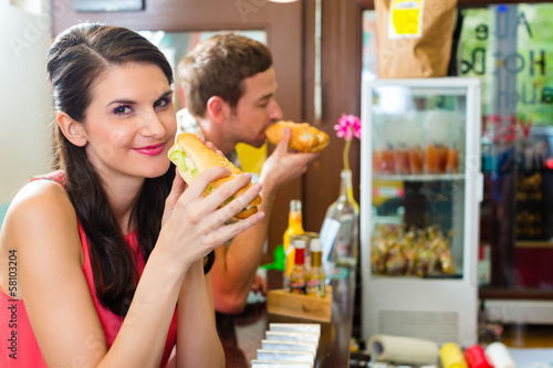 Photo: Kunden essen Hotdog in Fast Food Imbiss Kunden essen Hotdog in Fast Food Imbiss