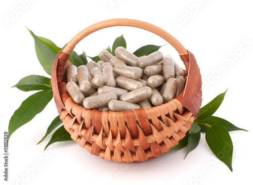 Photo: Herbal drug capsules in wicker basket. Alternative medicine conc Herbal drug capsules in wicker basket. Alternative medicine conc