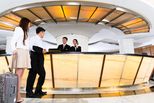 Photo: Asian Chinese couple arriving at hotel front desk Asian Chinese couple arriving at hotel front desk