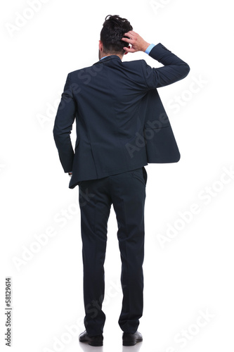 Photo: back of a young business man scratching his head back of a young business man scratching his head