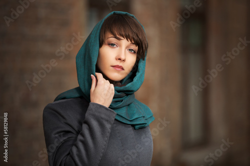 Photo: Sad young woman in grey classic coat at the wall Sad young woman in grey classic coat at the wall