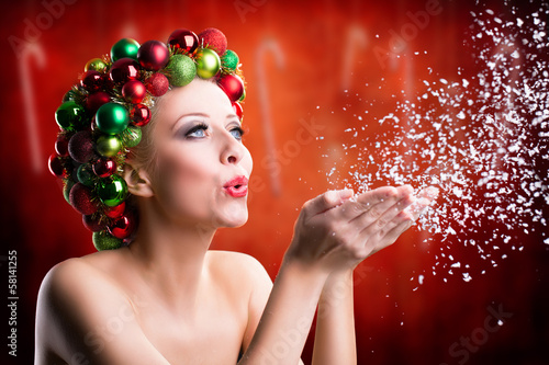 Photo: junge Frau mit Weihnachtskopfschmuck pustet Schnee junge Frau mit Weihnachtskopfschmuck pustet Schnee