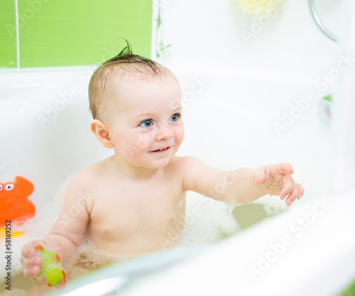 Photo: smiling baby girl taking bath and playing with toys smiling baby girl taking bath and playing with toys