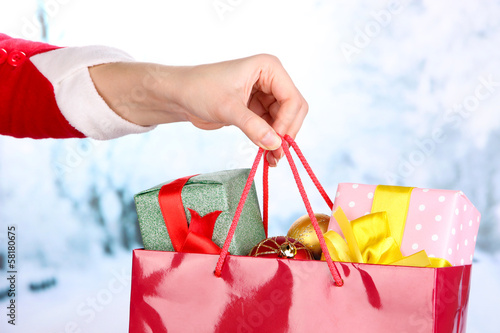 Photo: Hand holds package with New Year balls and gifts Hand holds package with New Year balls and gifts