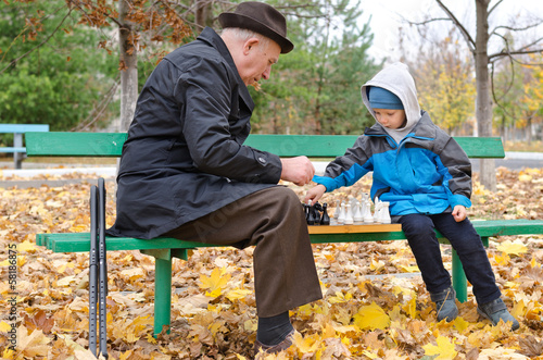 Photo: Disabled senior man teaching his grandson to play chess Disabled senior man teaching his grandson to play chess