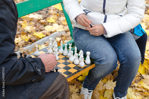 Photo: Elderly man a game of chess with woman park bench Elderly man a game of chess with woman park bench