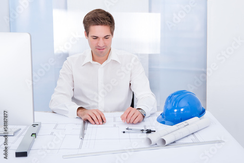 Photo: Young Architect Drawing Plan On Blueprint Young Architect Drawing Plan On Blueprint
