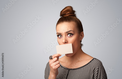 Photo: Cute girl holding white card at front of her lips with copy spac Cute girl holding white card at front of her lips with copy spac
