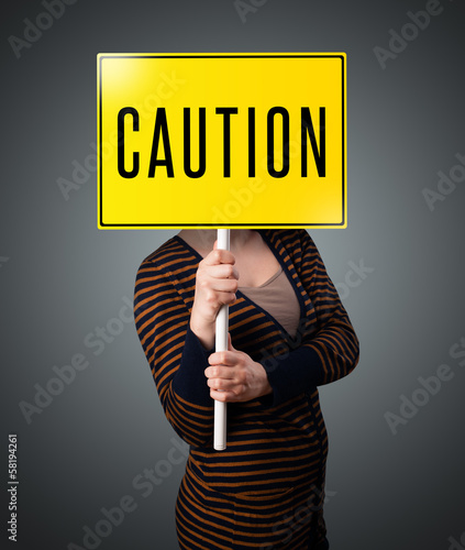 Photo: Young woman holding a caution sign Young woman holding a caution sign
