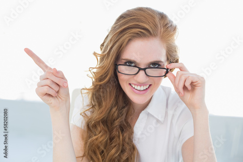 Photo: Cheerful businesswoman pointing to side in office Cheerful businesswoman pointing to side in office
